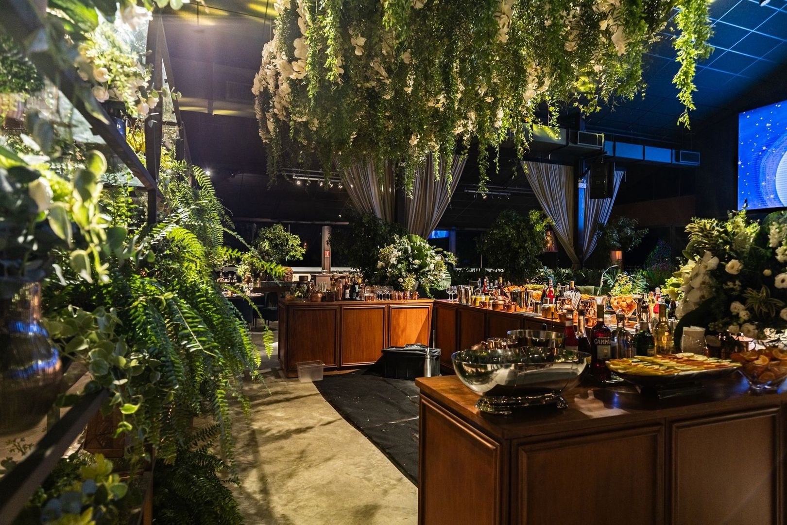Lushly decorated cocktail reception with buffet tables and floral greenery