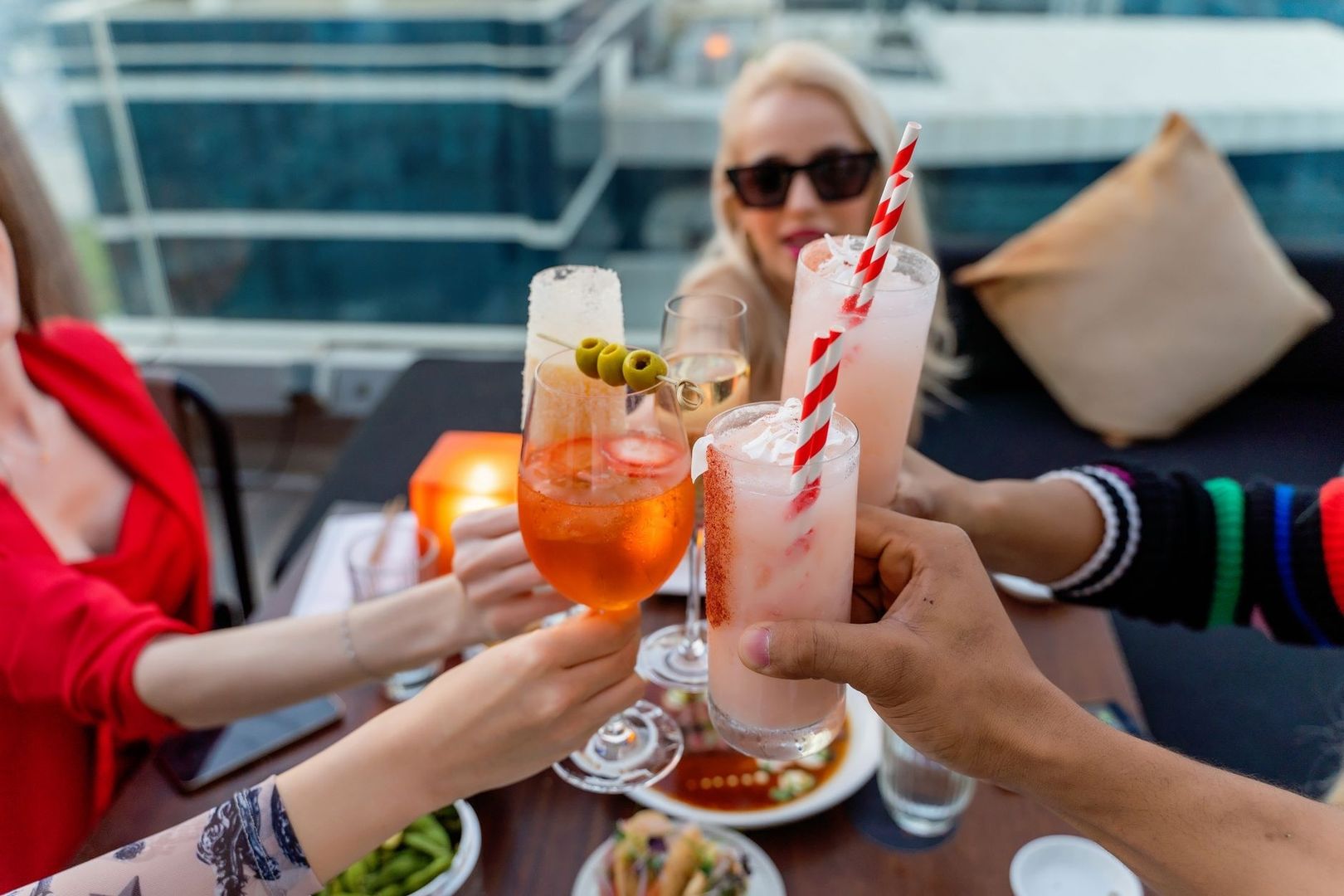 Friends raise colorful aperitif drinks on an outdoor terrace